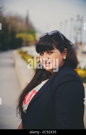 Glücklich lächelnd schöne übergewichtige junge Frau in dunkelblauer Jacke im Freien auf der Straße. Selbstbewusst Fett junge Frau. XXL Frau, plus Größe Frau. Stockfoto