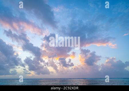 Wunderschöne rosa und orange Wolken bei Sonnenaufgang über der Karibik, Grand Cayman Island Stockfoto