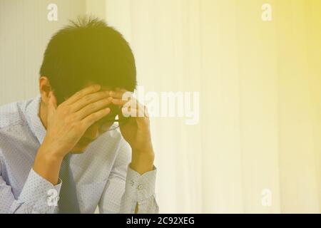 asiatischer Geschäftsmann legte seine Hand auf seinen Kopf, er fühlt sich schlecht über seine Firma Stockfoto