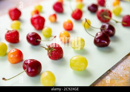 Verschiedene frische Beeren isoliert auf pstel Hintergrund, kreative flache Lay.Colorful Obst-Muster, Seitenansicht.Creative Sommer Food-Konzept Stockfoto