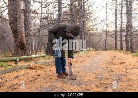 Jekaterinburg, Russland - 30. Oktober 2019: Im Herbst, in alten Stadtpark, ältere Frau mit Pack füttert kleine niedliche Eichhörnchen aus der Hand. Eichhörnchen steht Stockfoto