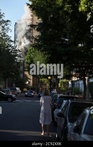 Rauch steigt aus dem Feuer am Grenfell Tower, einem 24-stöckigen Apartmentblock, der Teil des Lancaster West Estate in North Kensington, London, Großbritannien ist. Das Feuer wurde am frühen Morgen durch einen defekten Kühl-Gefrierschrank im vierten Stock ausgelöst. Sie breitet sich schnell über die Außenverkleidung und die Isolierung des Gebäudes aus. Das Feuer verursachte 72 Todesfälle, darunter die von zwei Opfern, die später im Krankenhaus starben. Mehr als 70 weitere wurden verletzt und 223 Menschen entkamen. Es war der tödlichste Strukturbrand im Vereinigten Königreich seit dem 1988 und der schlimmste Wohnungsbrand in Großbritannien seit dem Zweiten Weltkrieg Stockfoto