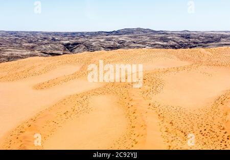 Typisches trostiges, arides Berggebiet der Namib-Wüste mit ockerfarbenem Sand auf geschichteten Felsen an der Skelettküste, Namibia, Südwestafrika Stockfoto