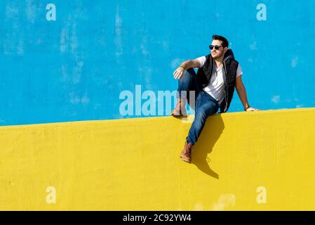 Bärtiger Mann in weißem T-Shirt, Jacke und Jeans auf blauem Hintergrund Stockfoto