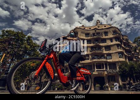 Barcelona, Spanien. Juli 2020. Ein Fahrradfahrer mit einer schützenden Gesichtsmaske passiert Gaudis 'La Pedrera', als Deutschland seine Reiseempfehlungen für drei spanische Regionen einschließlich Barcelona inmitten eines neuen Ansteckens von Coronavirus-Fällen aktualisiert. Quelle: Matthias Oesterle/Alamy Live News Stockfoto