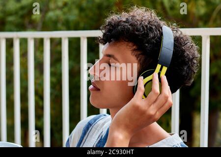 Junger Mann mit afro Haar schließt seine Augen beim Zuhören Zu Musik Stockfoto