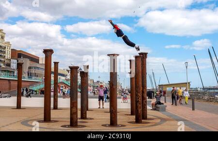 Brighton UK 28. Juli 2020 - EIN Freerunner springt an einem hellen und sonnigen, aber luftigen Tag über die Golden Spiral Pillars an der Küste von Brighton. Das Wetter wird in den nächsten Tagen im Südosten heiß, mit Temperaturen, die in einigen Gebieten über 30 Grad erreichen werden: Credit Simon Dack / Alamy Live News Stockfoto