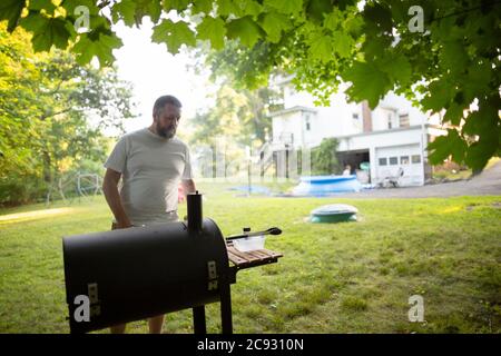 Erwachsene männliche steht Kochen Grill im Hinterhof bei warmem Wetter Stockfoto