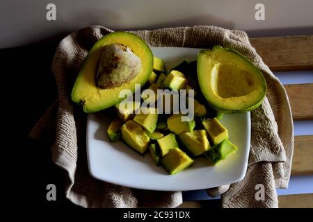 High-Angle-Aufnahme von aufgeschnittenen Avocado-Stücken auf einem Teller Mit halbierten Avocados Stockfoto