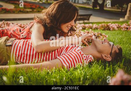 Stilvolles und modernes Paar, das im Park auf dem Rasen liegt und Zeit miteinander verbringt Stockfoto