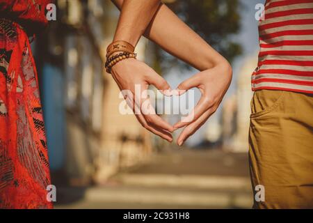 Nahaufnahme eines liebenden Paares, das mit Händen auf der Stadtstraße Herzform macht. Sommerzeit Stockfoto
