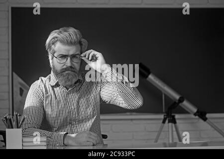 Der junge Professor hält einen Stapel Bücher und schaut über seine Brille. Stockfoto