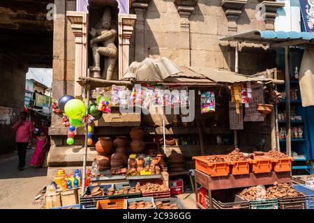 Trichy, Tamil Nadu, Indien - Februar 2020: Ein Geschäft, das Holztöpfe und Lampen unter einer alten Skulptur an den Wänden eines Tores zu einem Tempel in verkauft Stockfoto