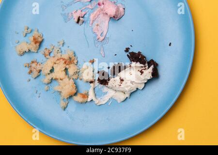 High-Winkel Nahaufnahme Schuss von Sahne und Krümel auf ein Blaue Platte auf gelber Oberfläche Stockfoto