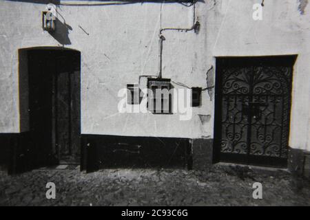 Feine Vintage-Schwarz-Weiß-Fotografie der 70er Jahre von Standard-Briefkästen, die an der Außenwand einer Wohneinheit hängen. Stockfoto