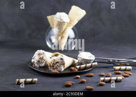 Eis Hintergrund in Zapfen. Frisches Eis zum Nachtisch. Mandeleis und Waffeleisen auf grauem Hintergrund. Copyspace Stockfoto