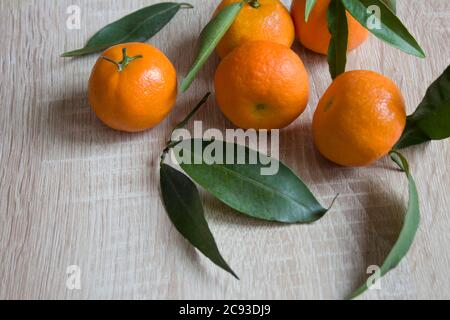 Mandarinen oder frische Mandarinen auf einem hölzernen Hintergrund. Mandarinen mit grünen Blättern. Organische Mandarinen. Copyspace Stockfoto