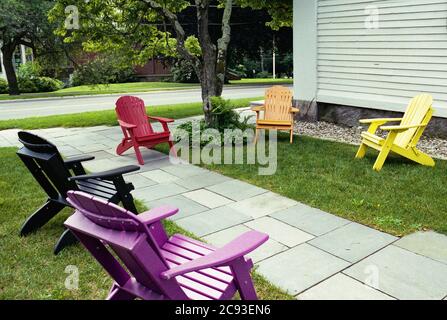 Bunte Adirondack Stühle sitzen leer, sechs Meter auseinander für soziale Distanzierung außerhalb einer weißen New England Kirche in der Sommersonne. Die Distanzierung Stockfoto