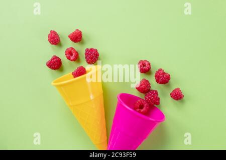 Bunte Waffelkegel mit frischen Bio-Himbeeren auf hellem Hintergrund. Sommerbeeren, Pop Art Design, kreative concept.greeting Karte, Platz für Text Stockfoto