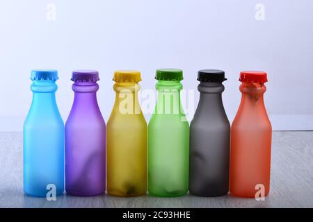Set von Flaschen in verschiedenen Farben. Reihe von bunten alkoholfreien Getränken auf hellgrauem Hintergrund. Regenbogen Komposition und Getränkekonzept. Energy Drinks Behälter mit verschiedenen Geschmacksrichtungen auf Holztisch Stockfoto