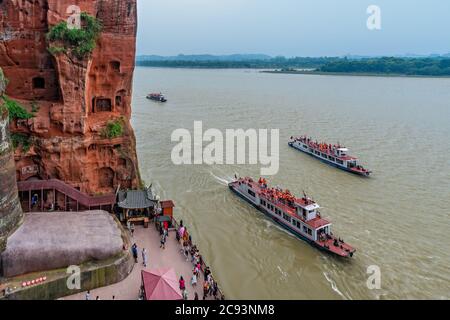 Leshan, China - Juli 2019 : Touristenboote mit Passagieren, die auf dem Min und Dadu Fluss unter der riesigen Buddha-Statue segeln Stockfoto