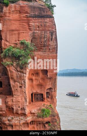 Leshan, China - Juli 2019 : Touristenboot mit Passagieren, die auf dem Min und Dadu Fluss unter der riesigen Buddha Statue segeln Stockfoto