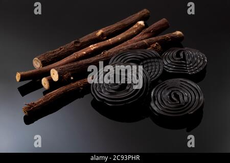 Kaubonbons und köstliches Dessertkonzept mit schwarzen Lakritzrädern oder Spiralen, die mit dem Extrakt der Wurzel der Glycyrrhiza Glabra Pflanze aromatisiert sind Stockfoto