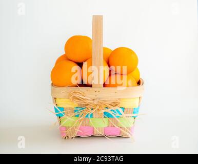 Gesunde Ostern - bunte Weide Ostern Korb gefüllt mit reifen saftigen Orangen, isoliert auf weiß Stockfoto