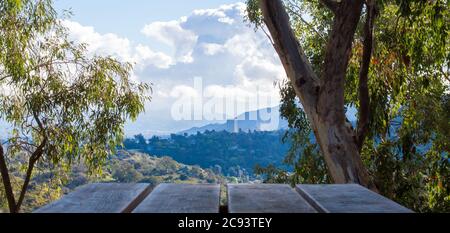 Blick von einem Picknicktisch auf hügelige grüne Hügel in der Nähe von Los Angeles mit hohen Gebäuden in der Ferne an einem bewölkten Tag Stockfoto