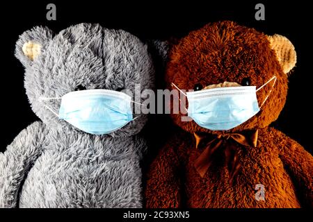 Zwei Teddybären tragen Gesichtsmasken isoliert auf schwarzem Hintergrund Stockfoto