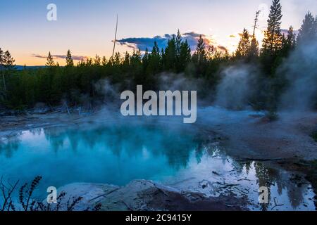 Reflexionen im Abendlicht an einem Thermalbecken im Norris Geyser Basin, Yellowstone National Park Stockfoto