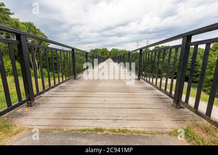 Metallbrücke über den Fluss. Fußgängerüberquerung über eine Schlucht in Mitteleuropa. Sommersaison. Stockfoto