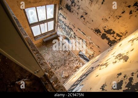 Blick hinunter in einen kleinen Raum in einem verlassenen Gebäude mit Trümmern und Graffiti bedeckt Stockfoto