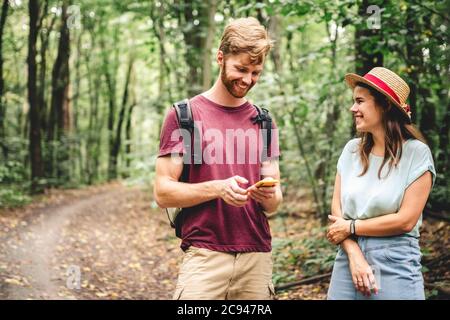 Wanderer mit mobilen gps für die Wegbeschreibung. Glückliches Paar überprüft Smartphone im Wald während der Rucksackreise. Junge fröhliche Paar mit gps-Karte Stockfoto