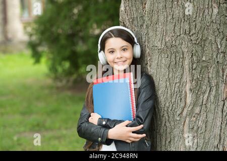 Mädchen hören Audio tragen Lehrbücher entspannend Park Hintergrund, Sound in ihrem Kopf Konzept. Stockfoto
