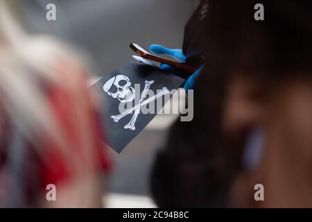 LONDON, ENGLAND - JJULY 28, 2020: Ein Fan, der vor dem Royal Court of Justice einen Jolly Roger Schädel und eine Kreuzknochen-Flagge in der Verleumdung von Johnny Depp schwenkt Stockfoto