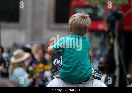 LONDON, ENGLAND - 28. JULI 2020: Ein kleiner Junge Fan winkt einen Jolly Roger Schädel und Kreuzknochen Flagge vor dem Royal Court of Justice in der Johnny Depp Stockfoto