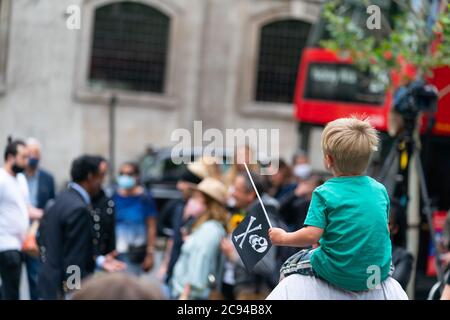 LONDON, ENGLAND - 28. JULI 2020: Ein kleiner Junge Fan winkt einen Jolly Roger Schädel und Kreuzknochen Flagge vor dem Royal Court of Justice in der Johnny Depp Stockfoto