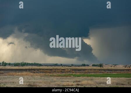 Ein riesiger Tornado bewegt sich schnell entlang einer Autobahn in Richtung einer Stadt Meilen vor. Stockfoto