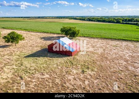 Eine verlassene alte Scheune mit dem Symbol von Texas auf dem Dach befindet sich in einem ländlichen Gebiet des Staates, eingerahmt von Ackerland. Stockfoto