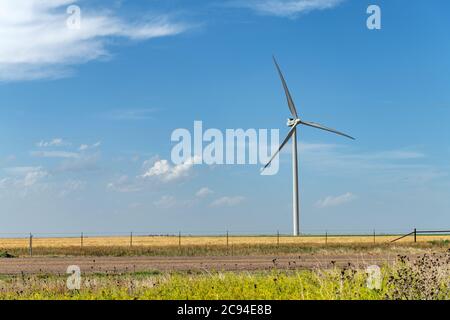 Ein eintönige Windturbinengenerator befindet sich mitten im ländlichen Mittleren Westen während des hellen Tages. Stockfoto