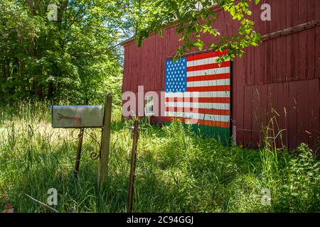 Eine rote Scheune mit einer handbemalten amerikanischen Flagge auf der Vorderseite des Gebäudes Stockfoto