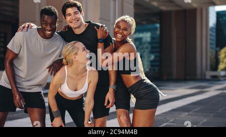 Gruppe von Männern und Frauen posieren für ein Foto nach dem Training im Freien. Multiethnische Freunde genießen sich nach dem Training. Stockfoto