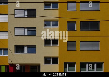 Außenansicht von vorne, typische Fassade der modernen Residenz oder Wohnung in der Stadt Europa mit rechteckigen Fenstern und verschiedenen Schatten der gelben Wand. Stockfoto