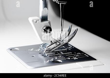3 - Schließen Makro Nähmaschinenbild mit selektivem Fokus zeigt Nadel, Faden, Presser Fuß, Futterhunde und Kehlplatte. Stockfoto
