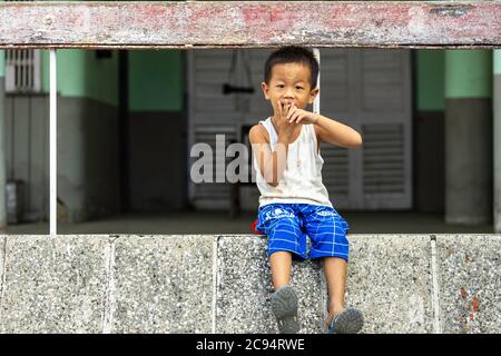 Sagaing/Myanmar-3. Oktober 2019: Ein Burmeser sitzt auf einem Bürgersteig und schaut auf den Fotografen. Stockfoto