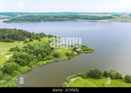 Blauer See und grüne Wälder an einem sonnigen Sommertag. Luftaufnahme von fliegender Drohne Stockfoto