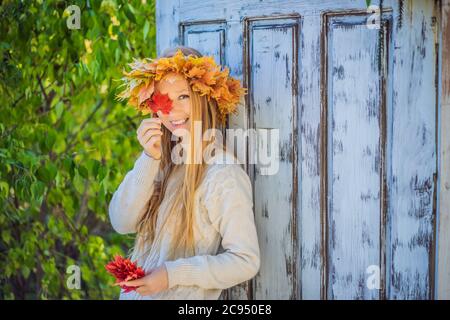 Outdoor Lifestyle Nahaufnahme Porträt von charmanten blonde junge Frau trägt einen Kranz aus Herbstblättern. In modischem Strickpullover. Kranz von Stockfoto