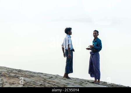 Sagaing/Myanmar-3. Oktober 2019: Zwei Burmesen stehen am Ufer des Flusses im Gespräch. Stockfoto