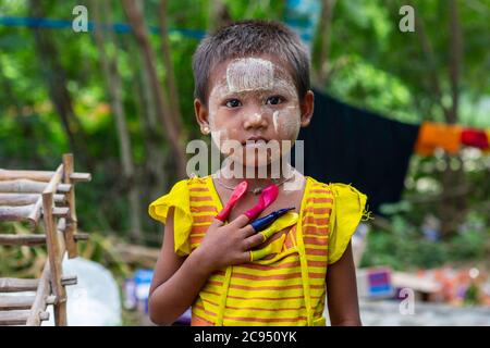 Sagaing/Myanmar-3. Oktober 2019: Ein burmesisches Mädchen trägt auffällige Farben und Finger in Luftballons verschiedener Farben. Stockfoto